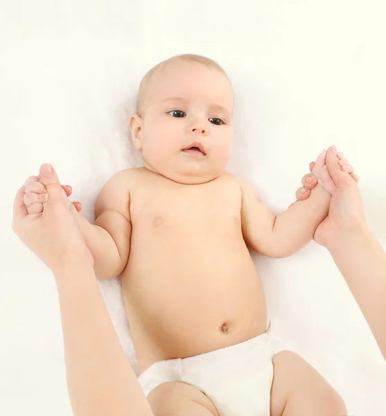Mother holding hands baby on white bed at home — Stock Photo, Image