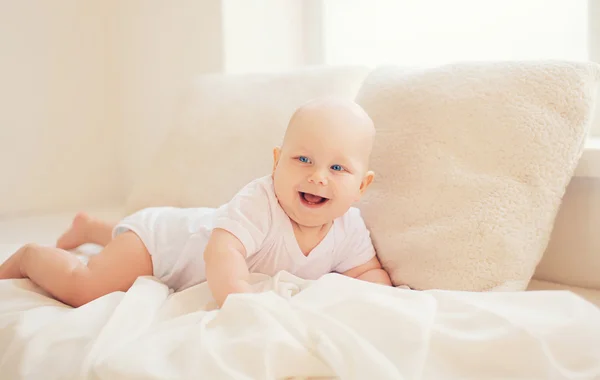 Feliz bebé sonriente se arrastra en casa en habitación blanca cerca de la ventana — Foto de Stock