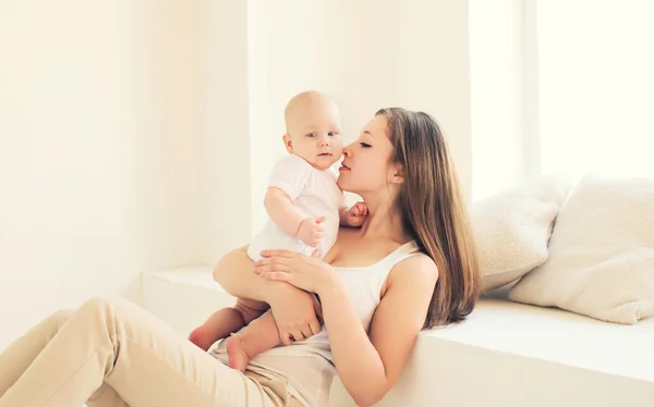 Jovem mãe e bebê felizes em casa na sala branca — Fotografia de Stock