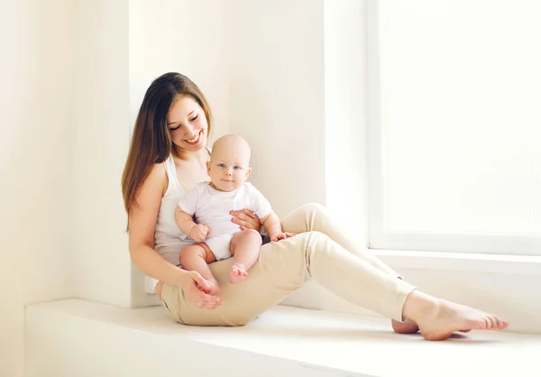 Joyeux jeune mère avec bébé à la maison en chambre blanche — Photo