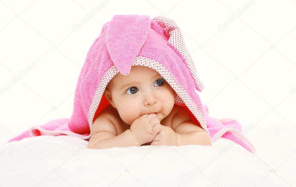 Portrait of cute baby under towel lying on bed 
