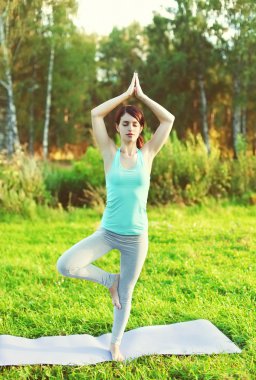 Kadının açık havada yaz çimenlerin üzerinde yoga egzersizleri yapması