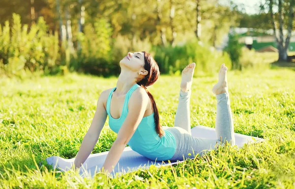 Donna che fa esercizi di stretching yoga sull'erba in estate soleggiata d — Foto Stock