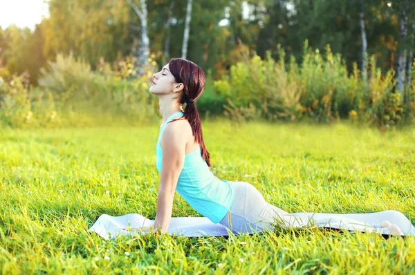Young woman doing yoga exercises on grass in summer — Stock Photo, Image