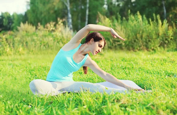 Young woman doing yoga exercises on grass in summer day — Stock Photo, Image