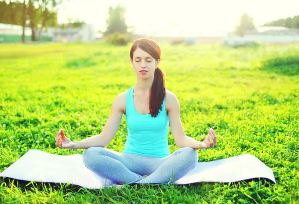 Yoga vrouw mediteert op gras pose lotus in zonnige dag — Stockfoto