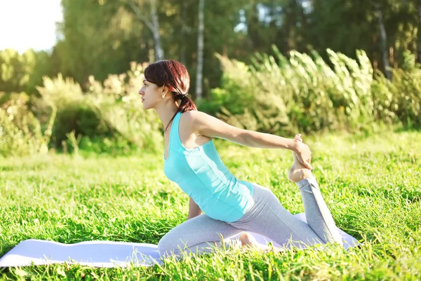 Frau macht Yoga-Übungen im Gras an Sommertagen, Profilansicht — Stockfoto