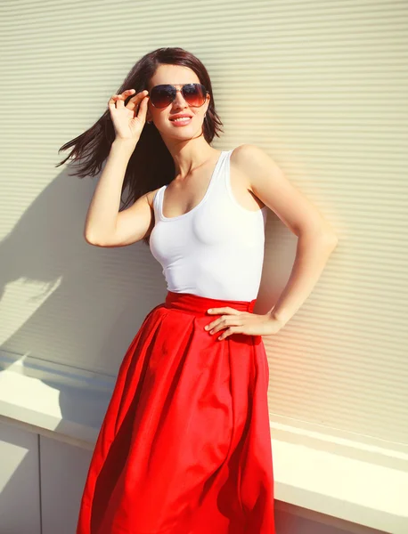 Όμορφη μελαχρινή γυναίκα, φορώντας ένα κόκκινο γυαλιά ηλίου και φούστα σε c — Φωτογραφία Αρχείου