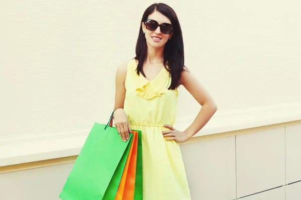 Hermosa mujer joven con un vestido amarillo con bolsas de compras —  Fotos de Stock