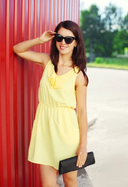 时尚微笑女人穿着一件黄色的连衣裙和太阳镜， — 图库照片