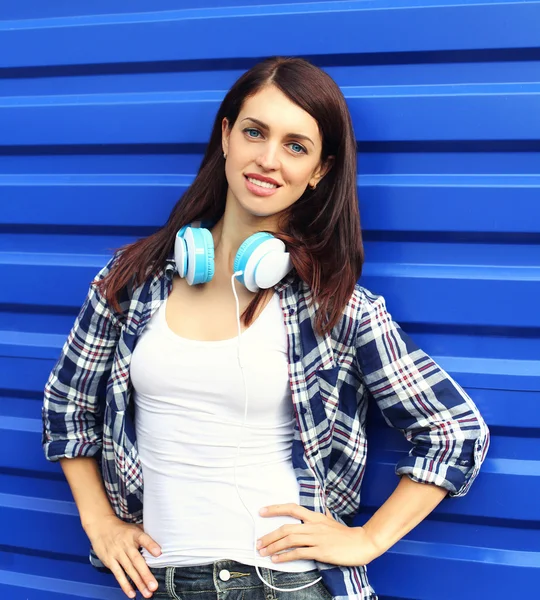 Гарненька брюнетка жінка в картатій сорочці з навушниками — стокове фото