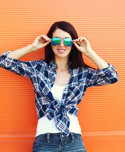 Hübsche brünette Frau mit Sonnenbrille über buntem Orange — Stockfoto