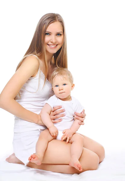 Glücklich lächelnde Mutter und Baby auf weißem Hintergrund sitzend — Stockfoto