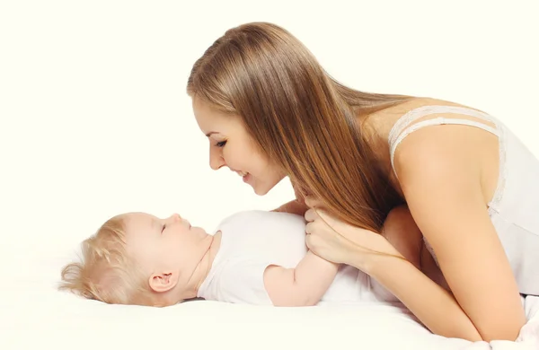 Gelukkig jonge moeder en baby samen liggend op bed — Stockfoto