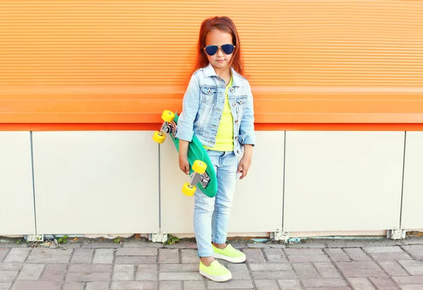 Mooi klein meisje kind met skateboard over oranje CHTERGRO — Stockfoto