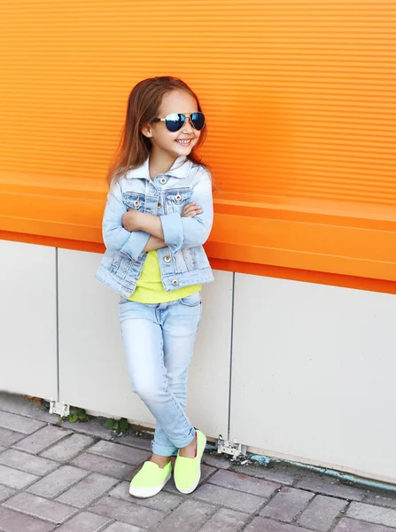 Schönes lächelndes kleines Mädchen mit Sonnenbrille und Jeans — Stockfoto