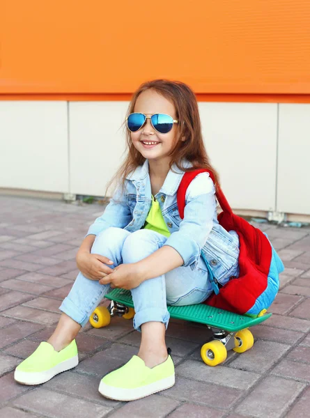 Стильная улыбчивая девочка с скейтбордом, веселящаяся в — стоковое фото