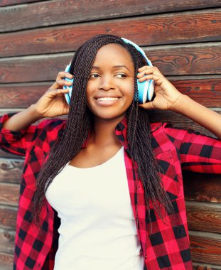 Çok gülümseyen Afrikalı kadın zevk kulaklıklarla dinler