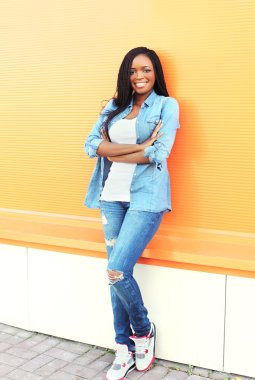 Beautiful smiling young african woman over orange background