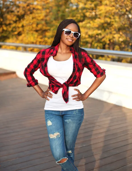 Mooie jonge Afrikaanse vrouw draagt een zonnebril en rode controleren — Stockfoto
