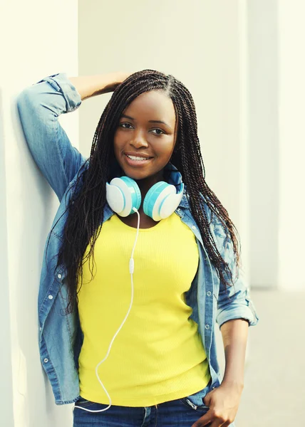 Красива усміхнена молода африканська жінка з навушниками в місті — стокове фото