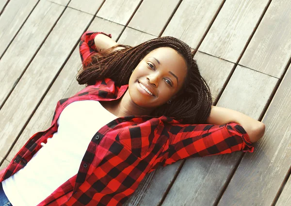 Bela sorridente jovem mulher africana relaxado no chão de madeira wi — Fotografia de Stock