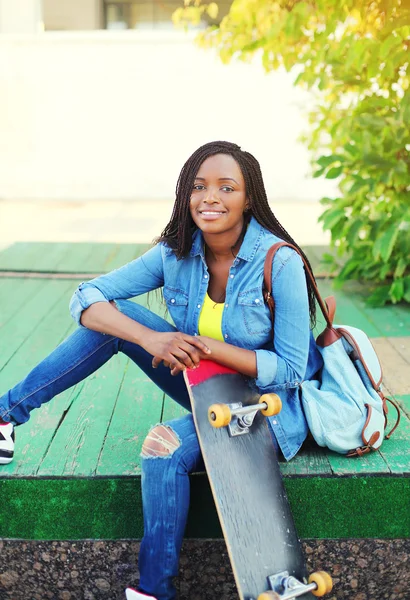 Schöne lächelnde junge Afrikanerin mit Skateboard im Freien — Stockfoto