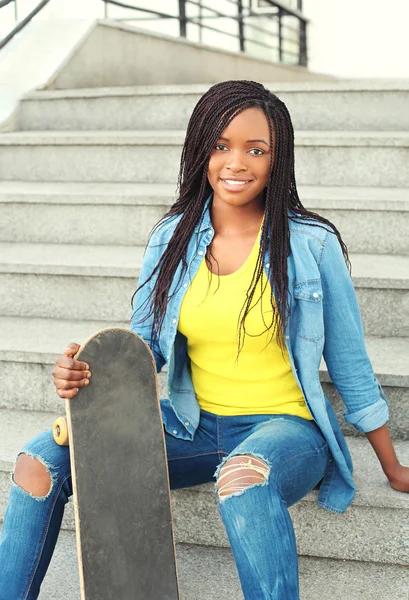 Fashion pretty young african woman with skateboard in city — Stockfoto