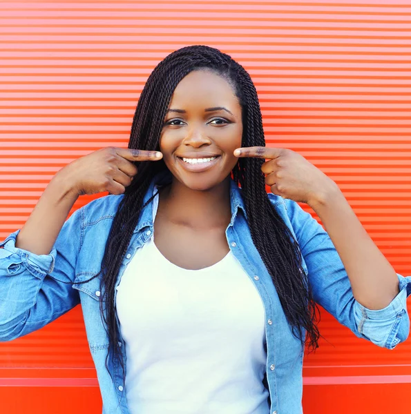 Schöne lächelnde Afrikanerin zeigt Finger auf Zähnen über Co — Stockfoto