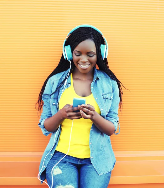 Piuttosto sorridente donna africana con le cuffie ascolta musica ov — Foto Stock
