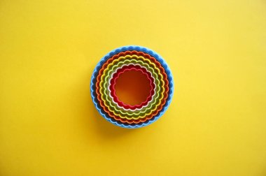 Sarı zemin üzerinde açık çalışma çemberi şeklinde kurabiyeler yapmak için çok renkli plastik kalıplar. Mutfak ya da parti konsepti. Kopyalama alanı olan düz.