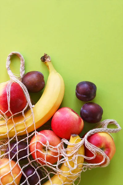 Maçãs Vermelhas Bananas Ameixas Saco Cordas Fundo Verde Brilhante Frutas — Fotografia de Stock