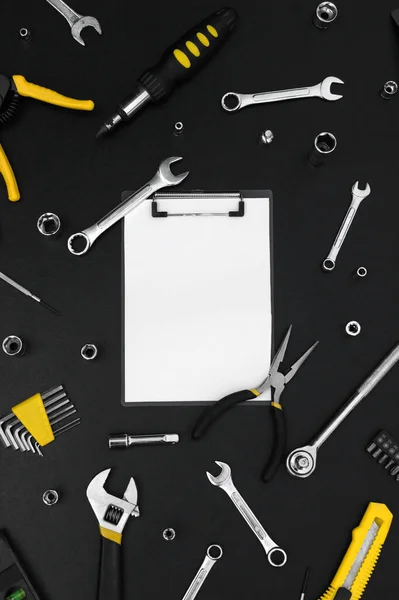 Notebook for writing, around various work tools on a black background. Repair and construction concept.
