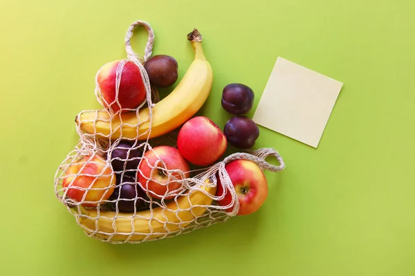 Maçãs Vermelhas Bananas Ameixas Saco Cordas Papel Branco Fundo Verde — Fotografia de Stock