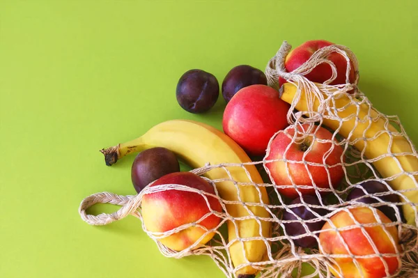 Maçãs Vermelhas Bananas Ameixas Saco Cordas Fundo Verde Brilhante Frutas — Fotografia de Stock