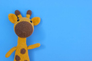 El yapımı çocuk oyuncağı. Mavi arka planda yumuşak örülü sarı zürafa..