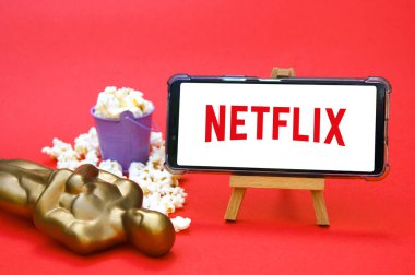 KHARKIV, UKRAINE - 1 Haziran 2020: Netflix stüdyo logosu, Oscar figürü ve patlamış mısırlı akıllı telefon. Film endüstrisi kavramı.