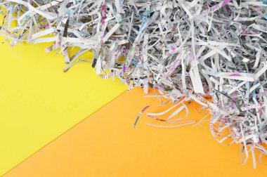Shredded paper on light yellow and orange background. Selective focus image.