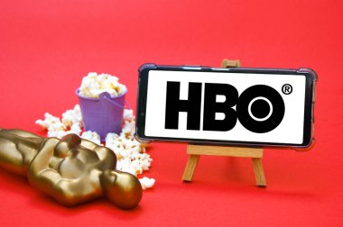 KHARKIV, UKRAINE - JUNE 1, 2020: smartphone with HBO film studio logo, Oscar figure and popcorn. Film industry concept.