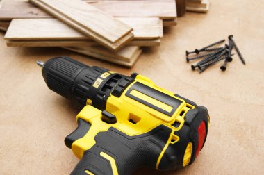 Tahta arka planda sarı-siyah tornavida, vidalar. Parke tahtaları.