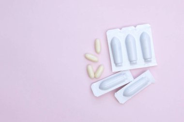 Kadın sağlığı için fitil şeklinde jinekolojik ilaçlar, pembe arka planda kapsüller. Vulvovaginal enfeksiyon tedavisi. Üst görünüm.