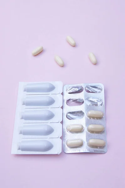 Gynecological medicines for women\'s health in form of suppository, capsules on pink background. Vulvovaginal infections treatment. Top view.