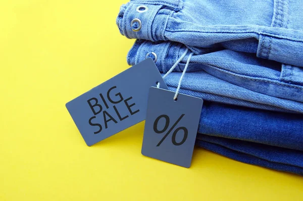 蓝色牛仔裤的细节 灰色标签和黄色背景的大减价 购物和打折的概念 黑色星期五 — 图库照片