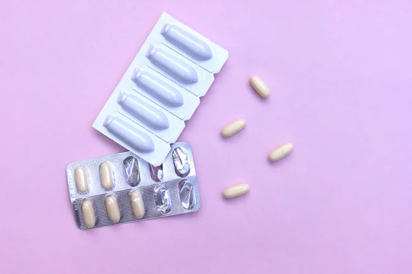 Gynecological medicines for women's health in form of suppository, capsules on pink background. Vulvovaginal infections treatment. Top view.