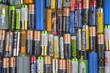 Kharkiv, Ukrayna - 20 Temmuz 2025: Kullanılmış AA bataryalar ve çevresel ve toprak toksik bataryaların yeşil arka planda düzgün bir şekilde imha edilmesi.