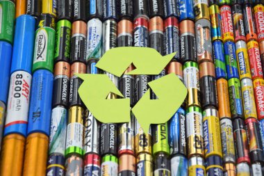 Kharkiv, Ukrayna - 20 Temmuz 2025: Kullanılmış AA bataryalar ve çevresel ve toprak toksik bataryaların yeşil arka planda düzgün bir şekilde imha edilmesi.