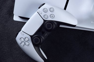 Kharkiv, Ukrayna - 10 Temmuz 2025: Beyaz Sony PlayStation 5 ve karanlık masa üzerindeki denetleyici.