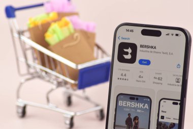 KHARKOV, UKRAINE - 18 Ağustos 2024: Akıllı telefonlu alışveriş arabası ekranda Bershka uygulaması açık.