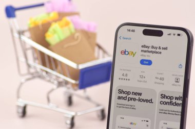 KHARKOV, UKRAINE - 18 Ağustos 2024: Akıllı telefonlu alışveriş arabası ekranda Ebay uygulaması açık.