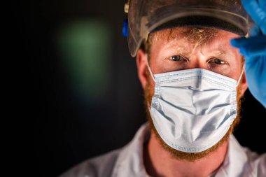 Avustralya 'da laboratuvar önlüğü ve eldiven giyerken maske ve yüz maskesi takan Covid doktor ve sağlık görevlisi..